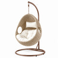 Sedia sospesa in rattan sintetico beige con cuscini bianchi e struttura in metallo
